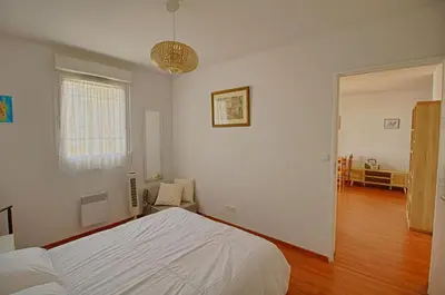 a bedroom with a white bed and a living room at Appartement Capo Rosso sanguinaires Ajaccio in Ajaccio
