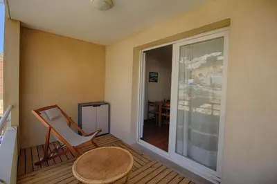 a balcony with a chair and a table and a window at Appartement Capo Rosso sanguinaires Ajaccio in Ajaccio