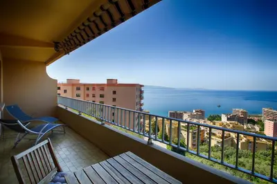 a balcony with a bench and a view of the ocean at Appartement Les Crêtes Sanguinaires Ajaccio in Ajaccio