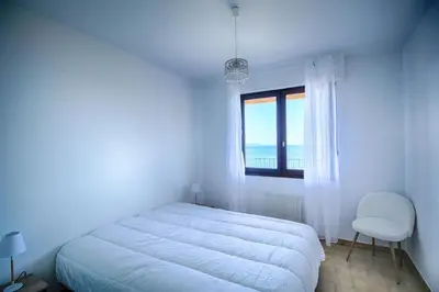 a white bedroom with a bed and a window at Appartement Les Crêtes Sanguinaires Ajaccio in Ajaccio