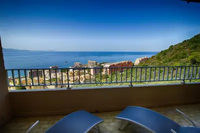 a balcony with two chairs and a view of the ocean at Appartement Les Crêtes Sanguinaires Ajaccio in Ajaccio
