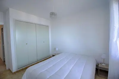 a white bed in a white bedroom with two lamps at Appartement Les Crêtes Sanguinaires Ajaccio in Ajaccio