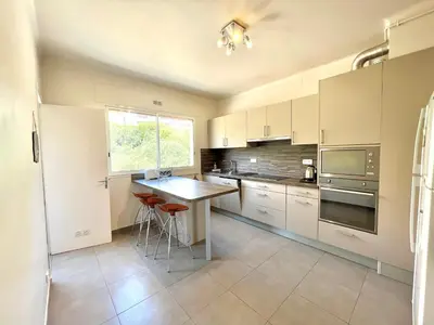 a kitchen with white cabinets and a table and a window at Appartement le Sicile sanguinaires Ajaccio in Ajaccio