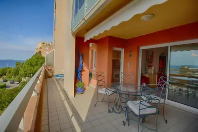 a balcony with a glass table and chairs at Appartement les Horizons sanguinaires Ajaccio in Ajaccio