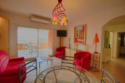 a living room with red chairs and a glass table at Appartement les Horizons sanguinaires Ajaccio in Ajaccio