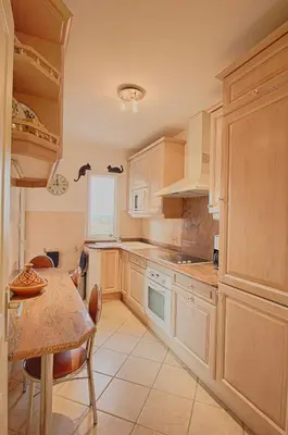 a kitchen with wooden cabinets and a table with chairs at Appartement les Horizons sanguinaires Ajaccio in Ajaccio
