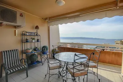 a balcony with a table and chairs and a view of the ocean at Appartement les Horizons sanguinaires Ajaccio in Ajaccio