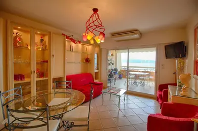 a living room with a glass table and red chairs at Appartement les Horizons sanguinaires Ajaccio in Ajaccio