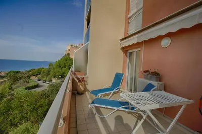a balcony with a table and chairs and the ocean at Appartement les Horizons sanguinaires Ajaccio in Ajaccio