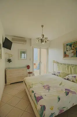 a bedroom with a bed and a dresser and a television at Appartement les Horizons sanguinaires Ajaccio in Ajaccio