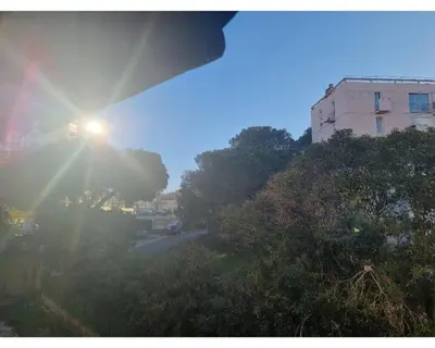 a sun is shining on a street with a building at Appartement proche plage in Ajaccio