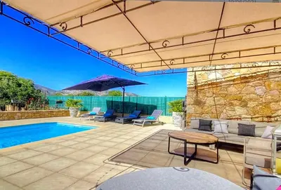 a patio with a pool and chairs and an umbrella at Villa terranga in Calenzana