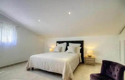 a bedroom with a white bed and a chair at Villa terranga in Calenzana