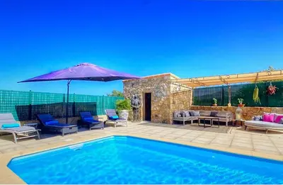 a swimming pool with an umbrella and chairs and a patio at Villa terranga in Calenzana