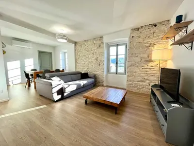 a living room with a couch and a tv at Joli T3 sur le port de Bonifacio avec vue mer in Bonifacio