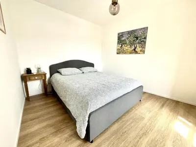 a bedroom with a bed and a painting on the wall at Joli T3 sur le port de Bonifacio avec vue mer in Bonifacio