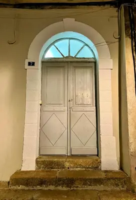 a large white door in a building with a window at Joli T3 sur le port de Bonifacio avec vue mer in Bonifacio