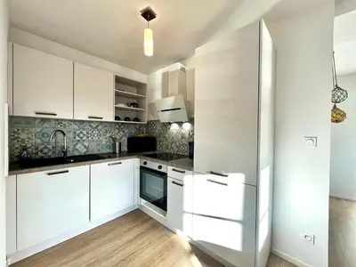 a kitchen with white cabinets and a sink at Joli T3 sur le port de Bonifacio avec vue mer in Bonifacio