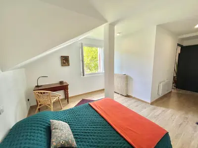 a bedroom with a bed and a desk and a window at Appartement rez de villa CORTE in Corte