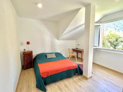 a bedroom with a bed and a desk and a window at Appartement rez de villa CORTE in Corte