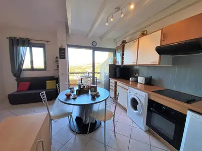a kitchen with a table and a living room at Appartement 102 Terra Bella 1 Porticcio in Porticcio