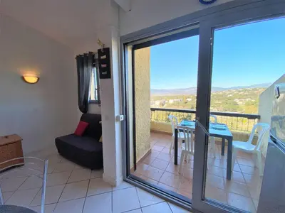 a room with a balcony with a table and a couch at Appartement 102 Terra Bella 1 Porticcio in Porticcio