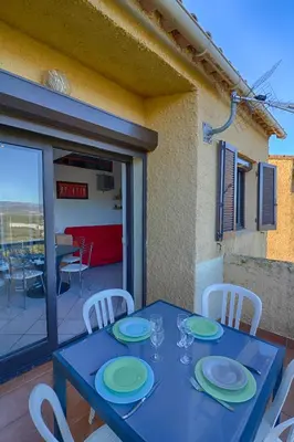 a blue table with plates and glasses on a balcony at Appartement 102 Terra Bella 1 Porticcio in Porticcio