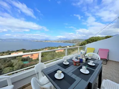 a table and chairs on a balcony with a view of the water at Appartement A Stagnola PORTICCIO in Porticcio