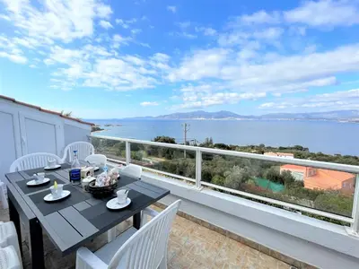 a balcony with a table and chairs and a view of the water at Appartement A Stagnola PORTICCIO in Porticcio