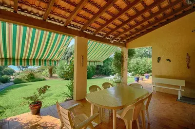 a patio with a table and chairs and a garden at VILLA 200 m de la plage La Liscia TIUCCIA in Casaglione