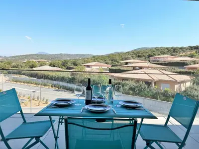 a blue table with two chairs and a bottle of wine at Appartement 2 pièces Les Jardins de Livia 1 PORTICCIO in Porticcio