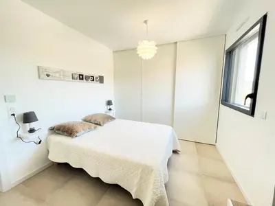 a white bedroom with a bed and a window at Appartement 2 pièces Les Jardins de Livia 1 PORTICCIO in Porticcio