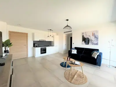 a living room with a black couch and a table at Appartement 2 pièces Les Jardins de Livia 1 PORTICCIO in Porticcio