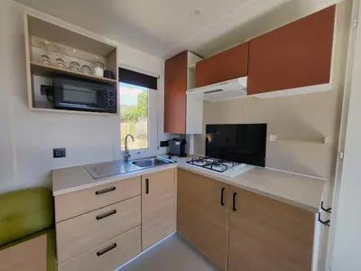 a small kitchen with a sink and a microwave at Camping Rondinara in Bonifacio