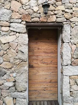 a wooden door in a stone building with a stone wall at Location Casa Di Lesia à Sotta / Porto-Vecchio in Sotta