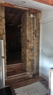 a room with a stone wall and stairs next to a door at Langhjuledda in Grosseto-Prugna