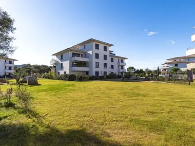 a large grassy field in front of a building at Apartment Domaine d'Arca G6 by Interhome in Porto-Vecchio