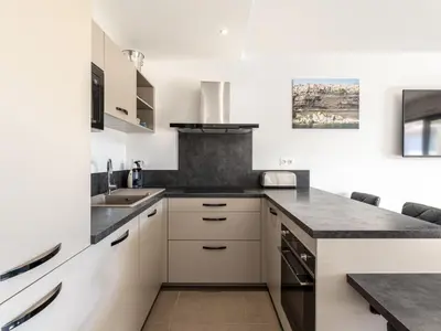 a kitchen with white cabinets and black counter tops at Apartment Domaine d'Arca G6 by Interhome in Porto-Vecchio