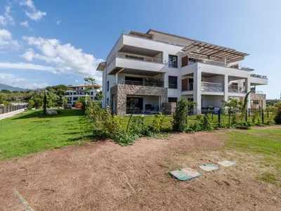 a large white house with a grassy yard at Apartment Domaine d'Arca G7 by Interhome in Porto-Vecchio