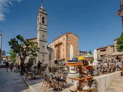 a clock tower in a city with tables and chairs at Apartment Domaine d'Arca G1 by Interhome in Porto-Vecchio
