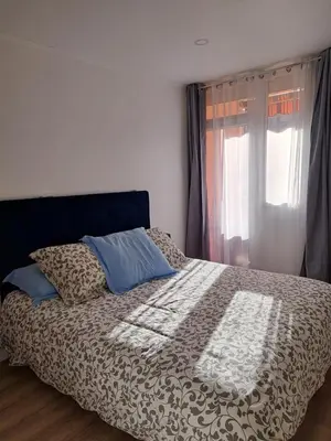 a bed with a comforter and a window at Casa D'Amore T3 in Ajaccio