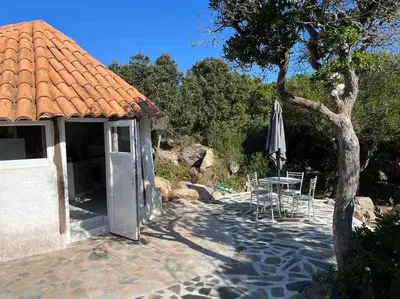 a patio with an umbrella and a table and a tree at Maison de vacances dans village AUTHENTIQUE Corse in Bonifacio
