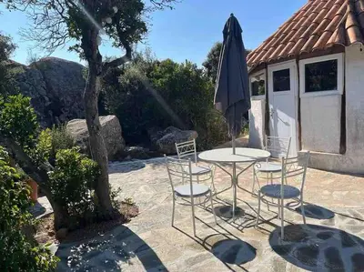 a table and chairs and an umbrella on a patio at Maison de vacances dans village AUTHENTIQUE Corse in Bonifacio