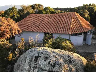 a house with a tile roof and a large rock at Maison de vacances dans village AUTHENTIQUE Corse in Bonifacio