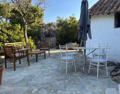 a patio with a table and chairs and an umbrella at Maison de vacances dans village AUTHENTIQUE Corse in Bonifacio