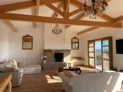 a living room with a stone fireplace and a chandelier at Villa proche plage extrême sud Corse in Monacia-dʼAullène