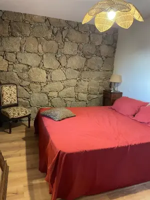 a bedroom with a red bed and a stone wall at Villa proche plage extrême sud Corse in Monacia-dʼAullène