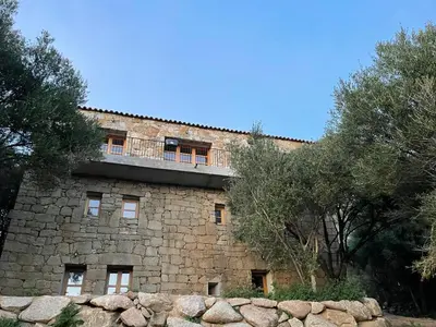 a stone building with a balcony on top of it at Villa proche plage extrême sud Corse in Monacia-dʼAullène