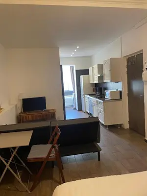 a living room with a couch and a kitchen at Studio cosy en centre d'Ajaccio in Ajaccio