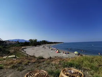 a beach with people laying on the sand and the water at Superbe appartement vue mer terrasse couverte face à la mer in Linguizzetta